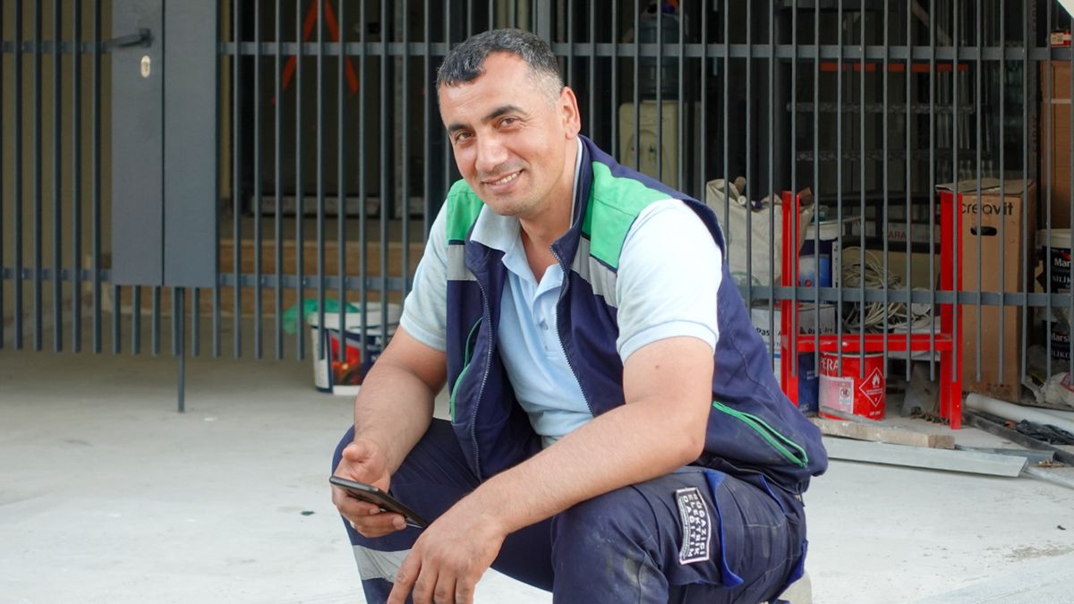 Lächelnder Handwerker prüft sein Smartphone auf der Baustelle